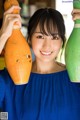 A woman in a blue dress holding two bowling pins.